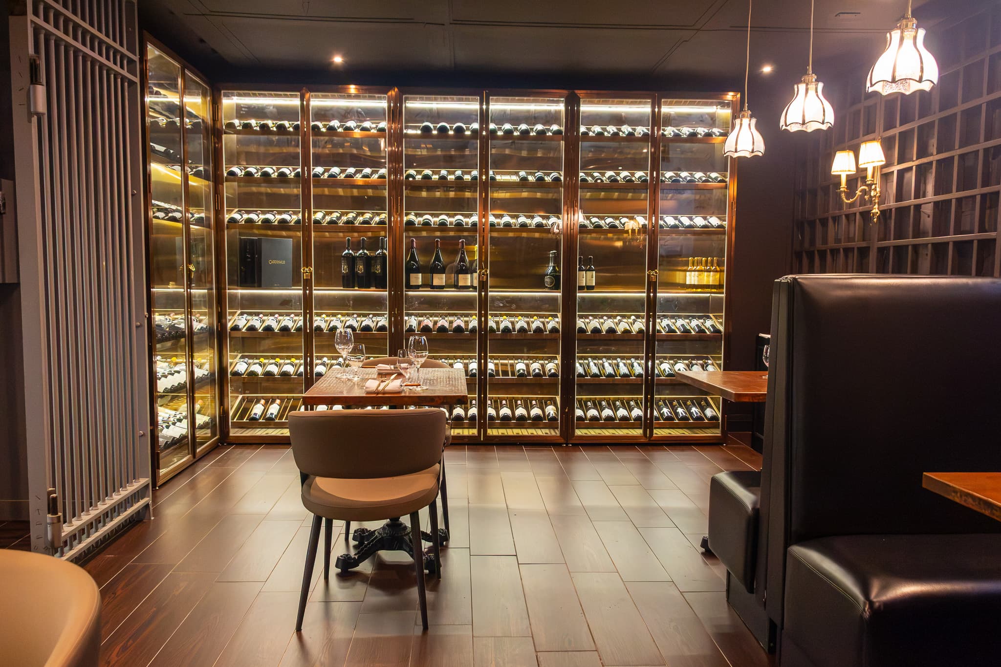 Dining table set against the illuminated wine wall at The Vault